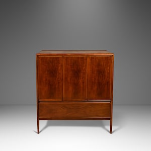 May include: A mid-century modern cabinet with three doors and a drawer. The cabinet is made of wood and has a rich brown finish.