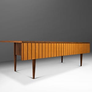 May include: A mid-century modern wooden console table with a slatted front and four legs. The table is made of a dark wood with a light wood finish on the front.