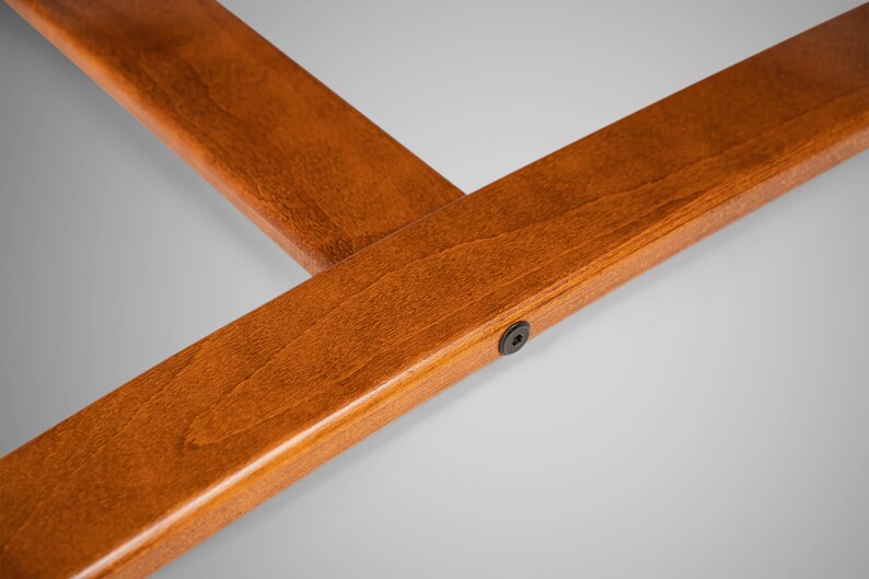May include: Close-up of a wooden frame with a dark brown stain. The frame has a smooth finish and a small black screw in the lower right corner.