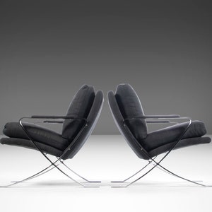 May include: Two black chairs with chrome frames. The chairs are angled towards each other and have a simple, modern design.