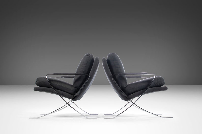 May include: Two black chairs with chrome frames. The chairs are angled towards each other and have a simple, modern design.
