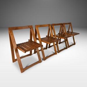 May include: Four wooden folding chairs in a row. The chairs are made of dark brown wood and have a simple, minimalist design.