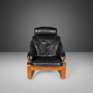 May include: A black leather armchair with a wooden frame. The chair has a high back and a comfortable seat.