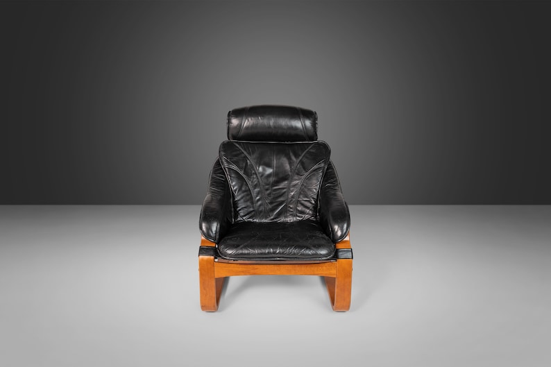 May include: A black leather armchair with a wooden frame. The chair has a high back and a comfortable seat.