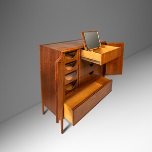 May include: A vintage wooden dresser with a mirrored top and multiple drawers. The dresser is made of dark wood and has a sleek, mid-century modern design.