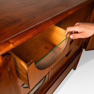 May include: A vintage wooden dresser with a curved design and glass-fronted drawers. The dresser has a rich brown finish and is in good condition.