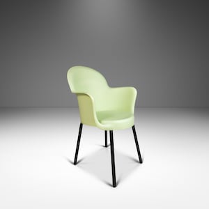 May include: A light green plastic chair with black metal legs. The chair has a rounded back and a wide seat.