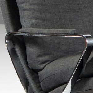 May include: Close-up of a gray fabric armchair with a chrome frame. The armrest is padded and the chair has a modern design.