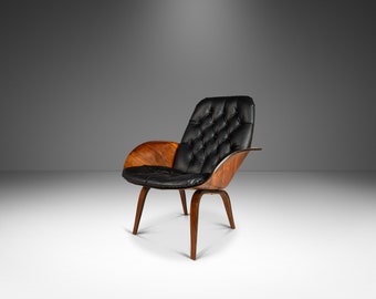 May include: A black leather armchair with a tufted back and a wood frame. The chair has a curved, wing-like armrest on one side.