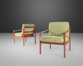 May include: Two mid-century modern armchairs with a light green fabric upholstery and dark wood frames.