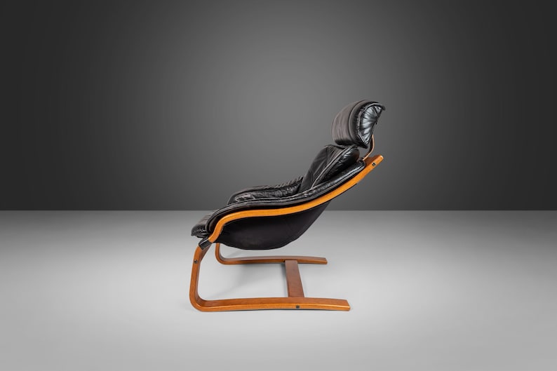 May include: A black leather armchair with a wooden frame and a curved base. The chair has a high back and a comfortable, padded seat.