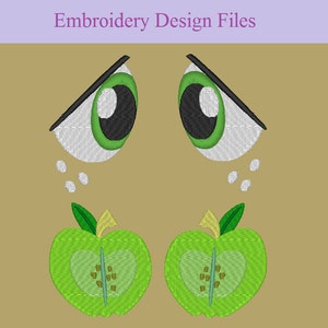 May include: An embroidery design featuring two sets of cartoon eyes and two green apple halves. The eyes have black pupils, green irises, and white eyelids with black angled eyebrows. The apples have green skin, yellow stems, and brown seeds. The text "Embroidery Design Files" is at the top.