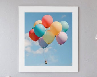 May include: A group of colorful balloons, including red, yellow, blue, green, and pink, are tied together and floating in a blue sky with white clouds. A small basket is attached to the bottom of the balloons.