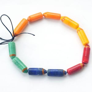 Op de afbeelding: Een kleurrijke armband gemaakt van oranje, groene, blauwe en rode kralen. De kralen zijn cilindrisch en hebben een gladde, gepolijste afwerking.