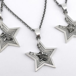 May include: Three silver necklaces with star-shaped pendants. Each pendant features a smaller star inside, with a detailed design.