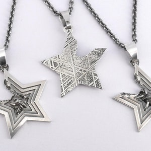 May include: Three silver star-shaped pendants on chains. The pendants are intricately designed with a layered star pattern. One pendant has a textured surface, while the other two have a more detailed design with a small insect inside.