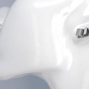 May include: A silver book-shaped stud earring. The earring is shown on a white mannequin head.