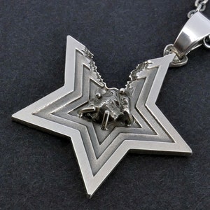 May include: A silver star-shaped pendant with a detailed, layered design. The star is open at the top, revealing a small, textured, silver object inside.