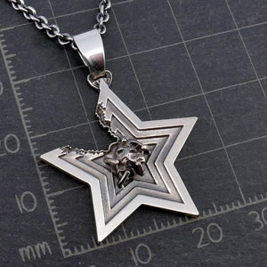 May include: A silver star-shaped pendant with a detailed design. The star is broken in the center, revealing a smaller, intricate design inside.