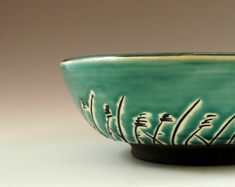 Big handthrown green bowl with black grass decor.