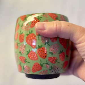 Green tumbler with strawberry pattern.