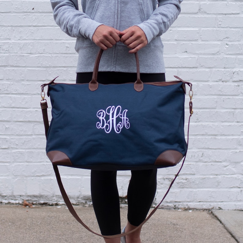 a woman holding a blue bag with a monogrammed monogrammed on it