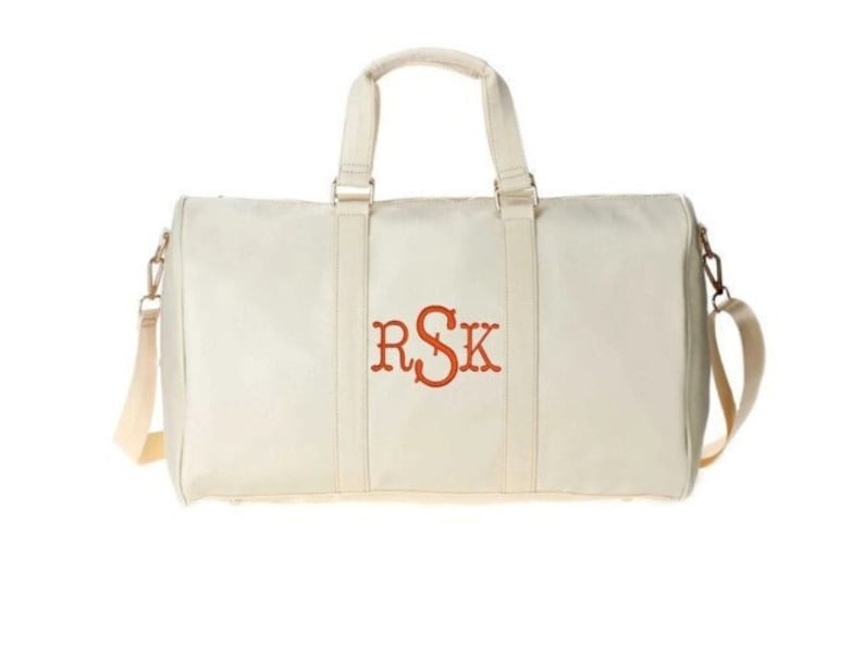 a white duffel bag with a red and orange logo