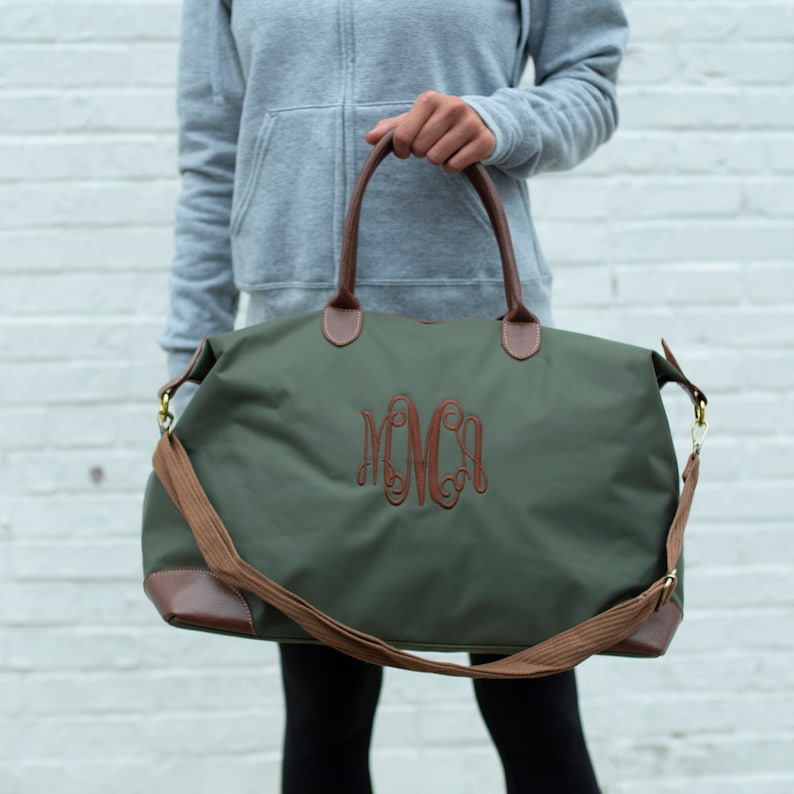 a woman holding a green duffel bag with a monogrammed monogrammed