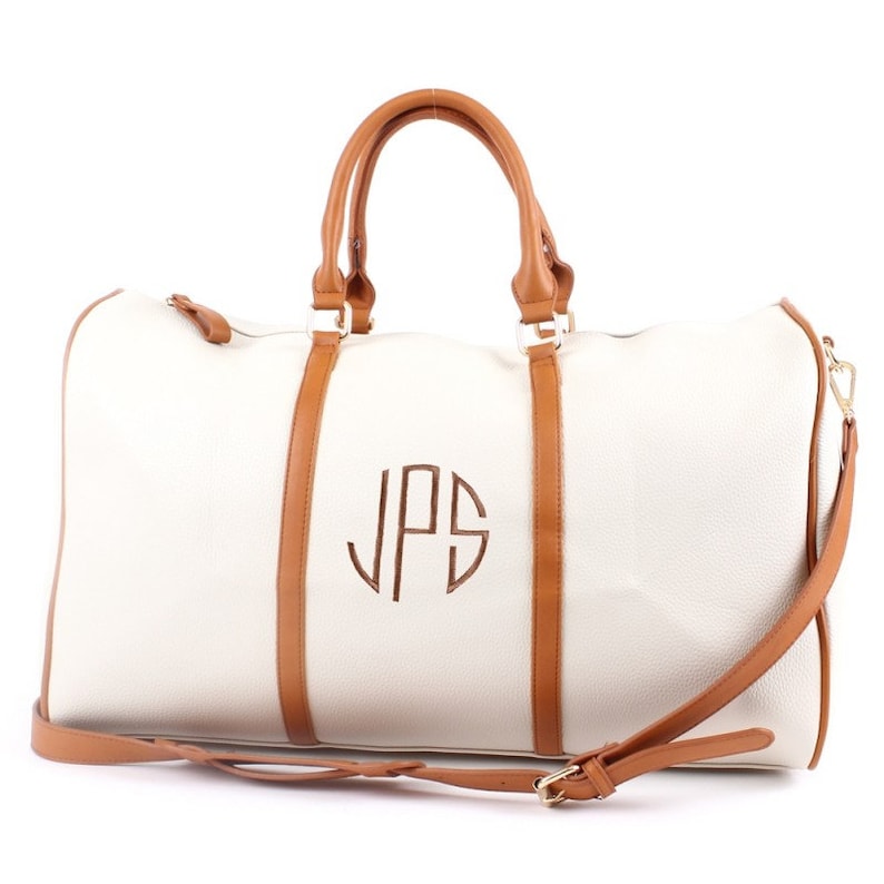 a white duffel bag with a brown handle