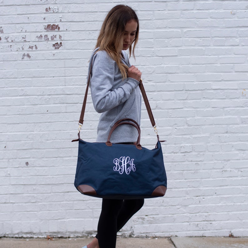 a woman carrying a blue bag with a monogrammed monogrammed on it