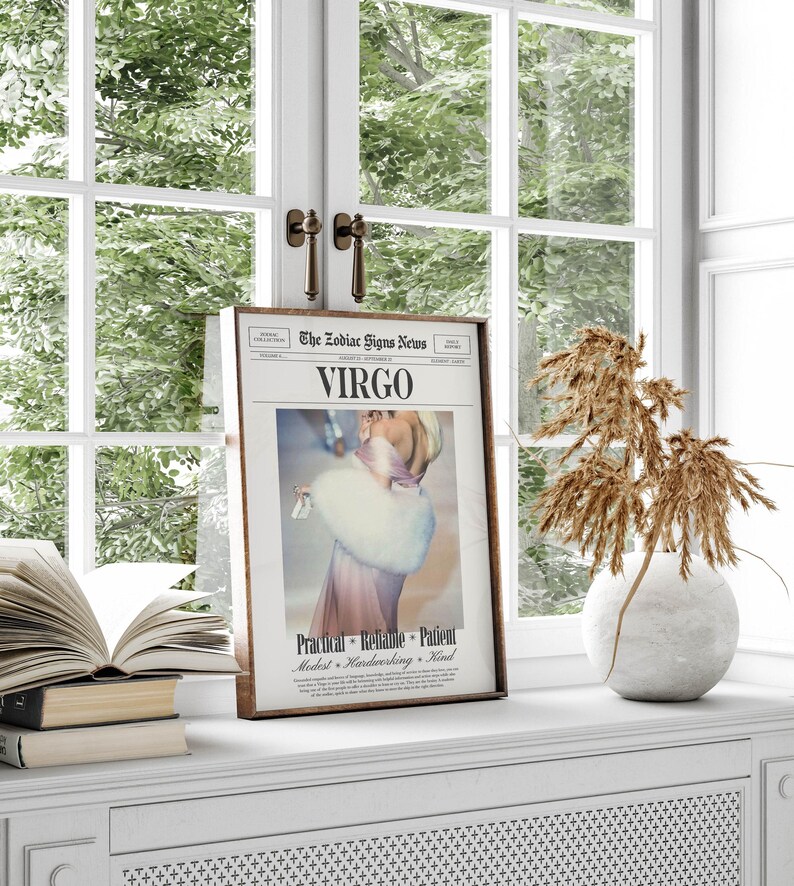 Op de afbeelding: Een ingelijste afdruk van een krantenpagina getiteld "The Zodiac Signs News" met het sterrenbeeld "Virgo". De afbeelding toont een vrouw in een roze jurk en witte bontjas. De print wordt weergegeven op een witte vensterbank met een vaas en boeken.