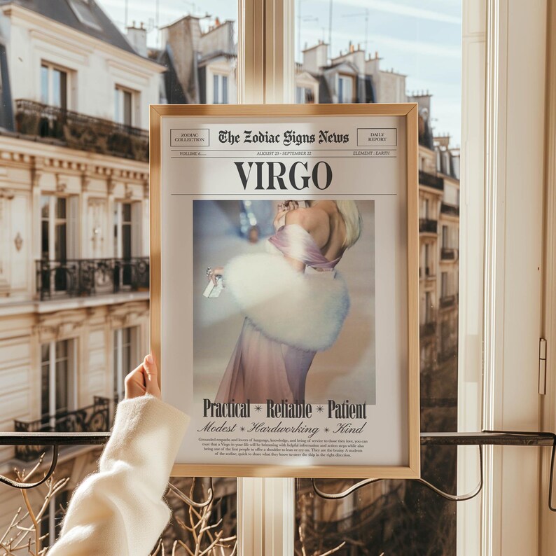 Op de afbeelding: Een ingelijste print met het sterrenbeeld Maagd, uit "The Zodiac Signs News". De afbeelding toont een vrouw in een roze jurk en een witte bontstola. De print bevat de woorden "Praktisch, Betrouwbaar, Geduldig, Bescheiden, Hardwerkend, Vriendelijk."