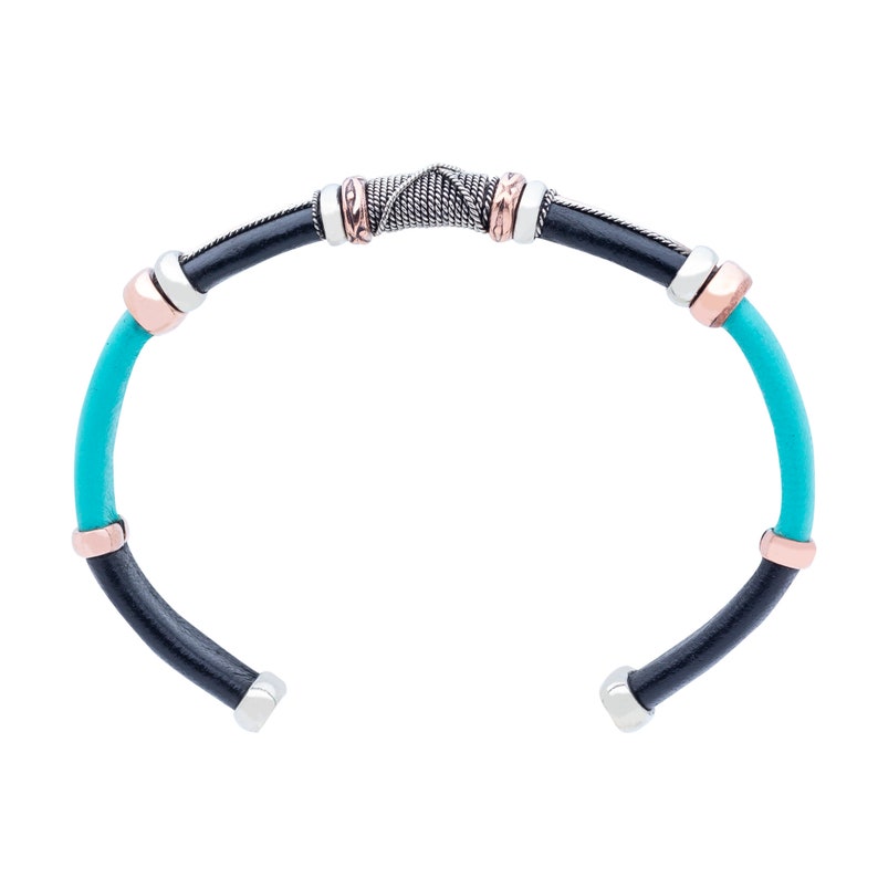 Puede incluir: Un brazalete de cuero turquesa con detalles en cuero negro y adornos de plata y cobre.