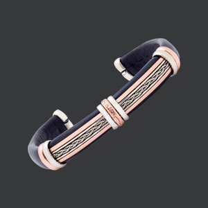 May include: A black leather bracelet with silver and rose gold accents. The bracelet has a braided design and a simple clasp.