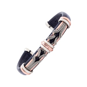 May include: A black leather bracelet with a silver and copper braided design. The bracelet has a decorative pattern of interwoven metal.