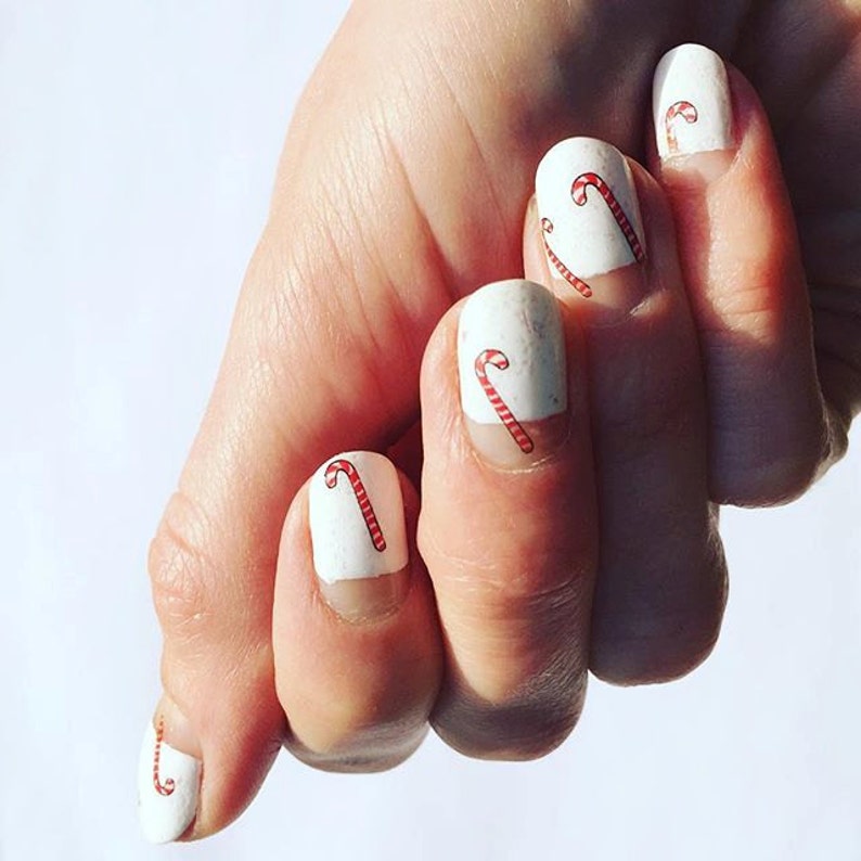 May include: White nail polish with red and white candy cane designs on each nail.