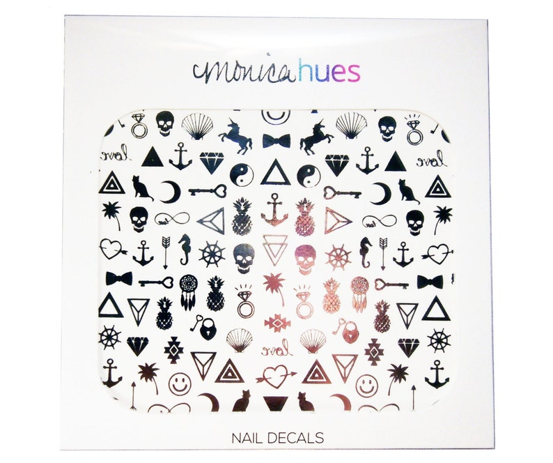 May include: A sheet of black and rose gold nail decals with a variety of symbols, including anchors, skulls, pineapples, hearts, and infinity signs. The sheet is labeled "monicahues NAIL DECALS".