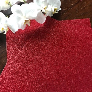May include: A stack of red glitter cardstock paper. The paper has a fine glitter finish and is perfect for crafting projects.