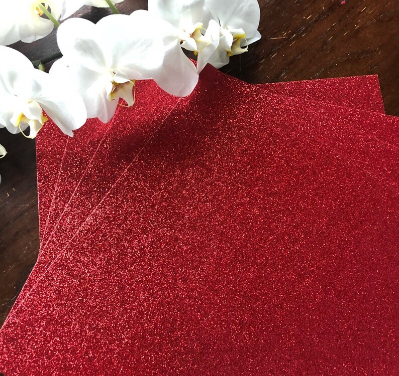 May include: A stack of red glitter cardstock paper. The paper has a fine glitter finish and is perfect for crafting projects.