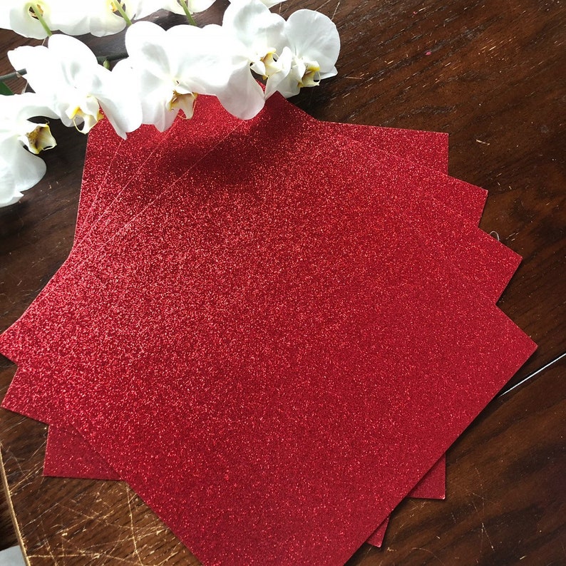 May include: A stack of red glitter paper sheets. The paper has a fine glitter finish and is perfect for crafting projects.