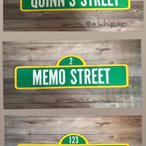 May include: Three street signs with a green and yellow design. The top sign reads "QUINN'S STREET" with the number "123". The middle sign reads "MEMO STREET" with the number "2". The bottom sign reads "DEUCE STREET" with the number "123".