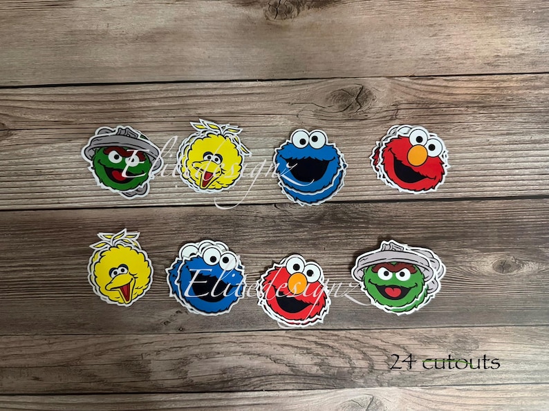 May include: A collection of colorful character cutouts, including Big Bird, Cookie Monster, Elmo, and Oscar the Grouch, arranged on a wooden surface. The image includes the text "24 cutouts".
