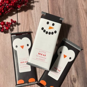 May include: Three chocolate bars wrapped in festive holiday packaging. Each bar features a different animal design: a snowman, a penguin, and another penguin. The wrappers have the text "a little treat for someone so sweet!" printed on them.