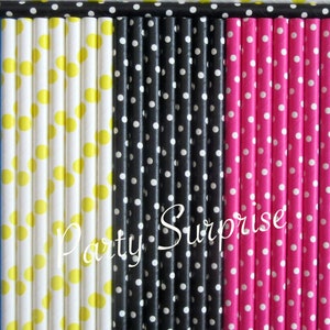 May include: A set of paper straws with polka dots in yellow, black and pink. The straws are arranged in three rows, with the yellow straws on the left, the black straws in the middle and the pink straws on the right. The text "Party Surprise" is printed in white on the black straws.