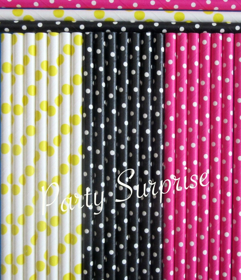 May include: A set of paper straws with polka dots in yellow, black and pink. The straws are arranged in three rows, with the yellow straws on the left, the black straws in the middle and the pink straws on the right. The text "Party Surprise" is printed in white on the black straws.