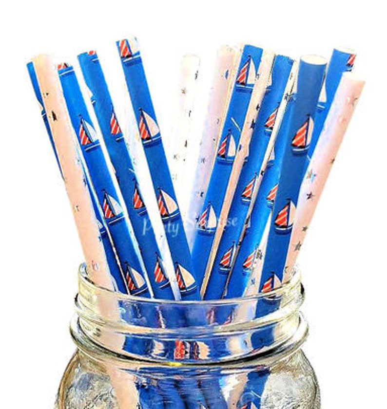 May include: A bundle of blue and white striped paper straws with red sailboats printed on them. The straws are in a clear glass jar.