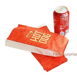 以下が含まれることがあります： ホットドッグのデザインが施された赤と白の紙袋。袋には「ホットドッグ」の文字が印刷されています。背景にはコカ・コーラの缶があります。