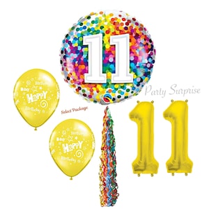 May include: Eleventh birthday party decorations with a large confetti balloon with the number 11, two yellow number 11 balloons, two yellow balloons with the text "Happy Birthday", and a rainbow streamer.