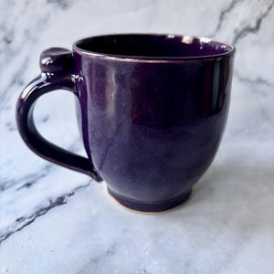 May include: A set of three ceramic mugs with a speckled, matte finish. The mugs are in shades of cream, light gray, and dark gray. Each mug has a simple, minimalist design, perfect for coffee or tea.