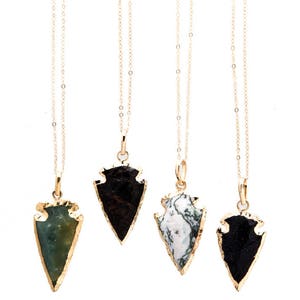 Può includere: Quattro collane con catena d'oro e ciondoli a forma di punta di freccia. Le punte di freccia sono realizzate in diversi tipi di pietra, tra cui verde, nero, bianco e una miscela di bianco e verde.
